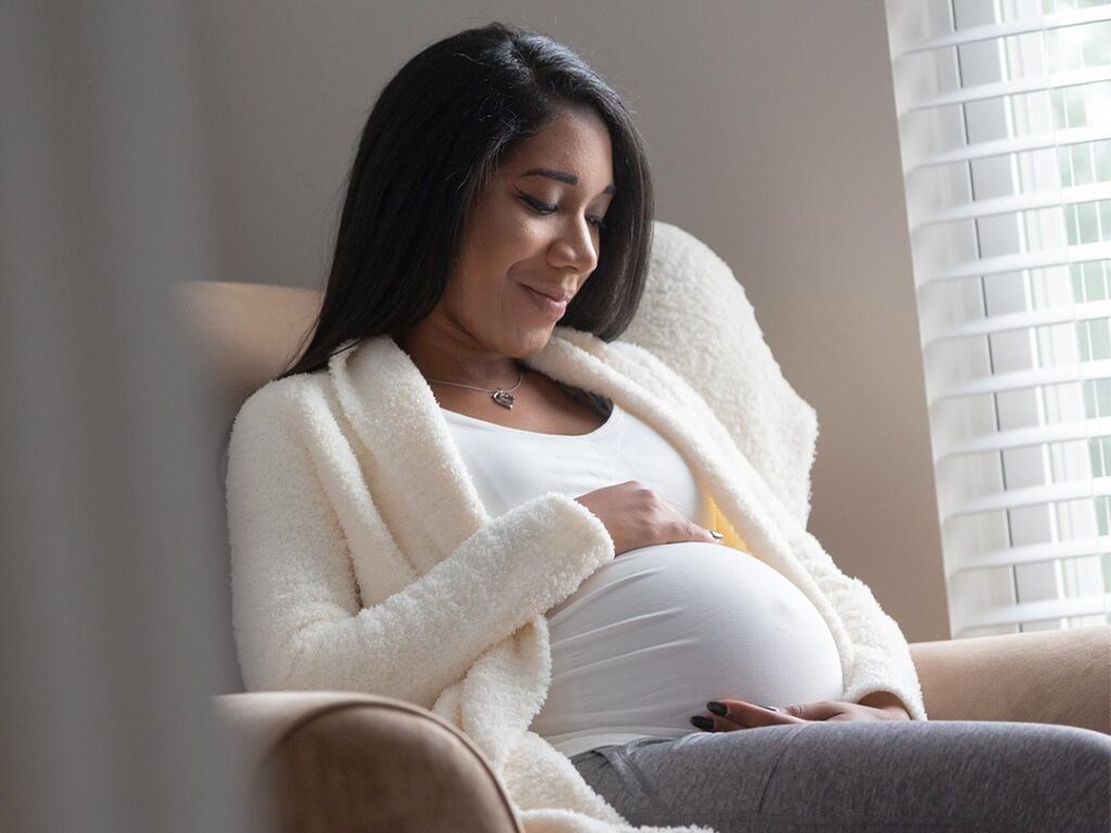 A pregnant woman peacefully seated on a couch, radiating a sense of calmness and anticipation