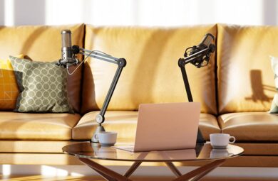 A laptop and microphone placed on a table in front of a couch, ready for a productive and comfortable podcast recording session